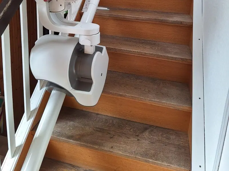 Seated stairlift parked on a straight indoor staircase